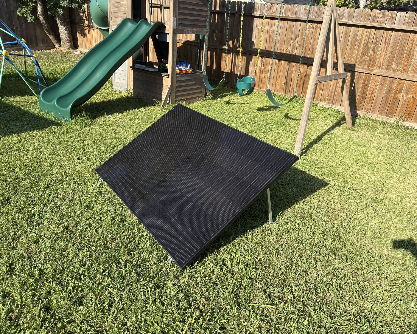 A solar panel on its ground frame beside the house